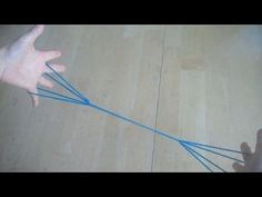 two hands reaching for something on the floor with blue string attached to it's sides