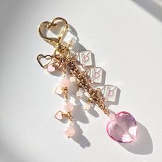 a key chain with charms attached to it on top of a white surface next to a pink heart