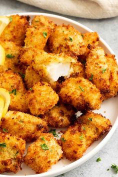 a white plate topped with tater tots and lemon wedges