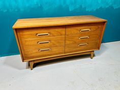 a wooden dresser sitting on top of a white floor next to a blue painted wall