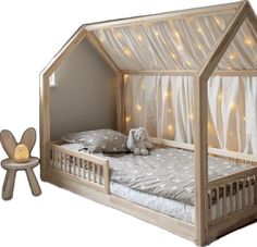 a wooden bed with white curtains and a teddy bear sitting on the floor next to it