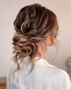 a woman with long hair in a low bun braided into an up - do