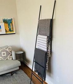 a living room with a chair, rug and towel rack next to a white wall