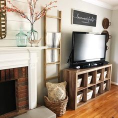 a flat screen tv sitting on top of a wooden shelf in front of a fire place