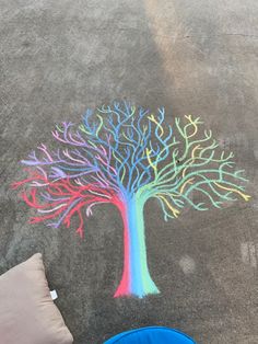 a child's chalk drawing of a tree on the ground next to a blue bowl