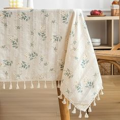 a white table cloth with flowers and tassels on it sitting on a wooden chair