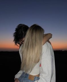 two people embracing each other in front of a sunset