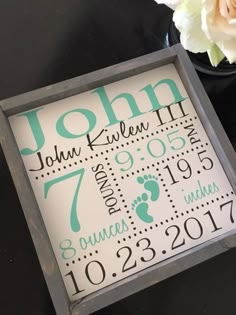 a baby's birth announcement is displayed in a shadow box next to a flower