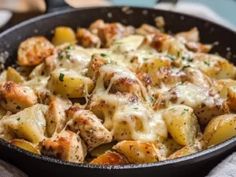 a skillet filled with chicken and potatoes covered in cheese