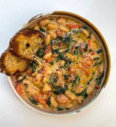 a bowl filled with beans and spinach next to two pieces of bread on top of it