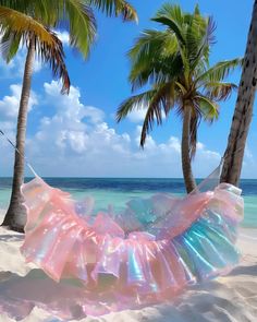 a woman laying in a hammock on the beach with palm trees behind her