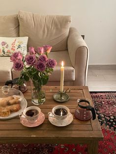 a table topped with coffee cups and pastries next to a vase filled with roses