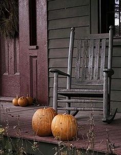 two pumpkins are sitting on the porch of a house next to a rocking chair