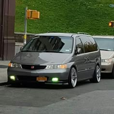 two cars are parked on the side of the road in front of a green wall