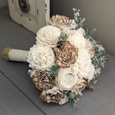 a bridal bouquet with white flowers and greenery sits on a wooden table next to an old door