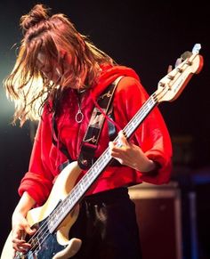 a man with long hair playing an electric guitar