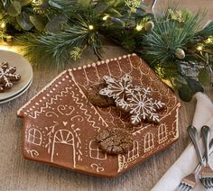 a gingerbread house is decorated with icing and snowflakes on the table