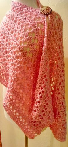 a pink crocheted shawl on a mannequin