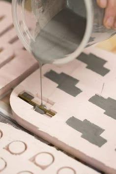 a person is using a paint roller to paint the floor tiles with gray and white designs