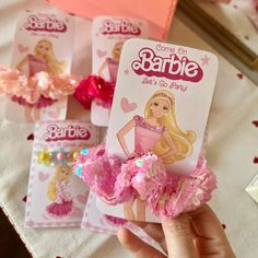 there is a barbie doll with pink flowers in her hair and some cards on the table