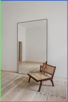 a chair sitting on top of a wooden floor next to a large mirror in a room