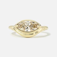 a yellow gold ring with an oval cut diamond in the center and twisted band around it