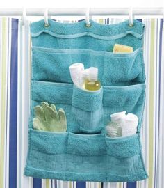 a blue towel hanging on the side of a shower curtain with soap, toothbrushes and gloves in it