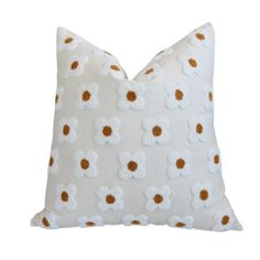 a white pillow with brown and white flowers on the front, against a white background