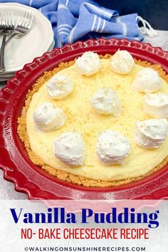 a cheesecake with whipped cream on top in a red pie pan next to silverware