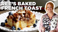 a woman standing in front of a cake on a plate with blueberries and bananas