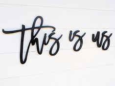 this is us sign hanging on the side of a white wall with black lettering that says it's us