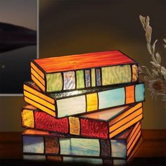 a multi - colored stained glass lamp sitting on top of a table next to a vase with flowers