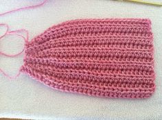 a knitted pink hat sitting on top of a table next to knitting needles and yarn