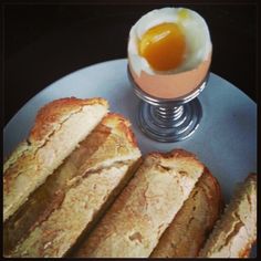 a plate with bread and an egg on it next to a glass filled with liquid