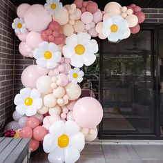 a bunch of balloons that are on the side of a building with flowers hanging from them