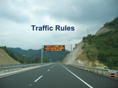 a highway sign that says traffic rules on the side of it, with mountains in the background