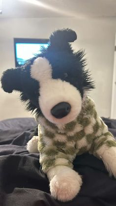 a black and white stuffed dog sitting on top of a bed