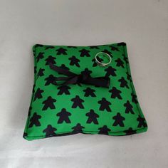 a green and black square shaped pillow with a ring on it