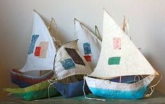 three sailboats are sitting on top of a wooden table and one is made out of fabric