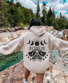 Moon Phases Moth Hoodie This Moth and Moon Phases Hoodie is perfect for adding a touch of mysticism to your style. The Moon Phases design on this sweatshirt represents the cyclical nature of life. It is a reminder to embrace the changes that come with each phase of our lives and to find beauty in the journey. Available in a range of sizes and colors, our Moth and Moon Phases Hoodie is a unique and eye-catching piece that's sure to become a staple in your wardrobe. This hooded sweatshirt is made from soft and durable material, making it perfect for any occasion, whether you're lounging at home or out and about. Treat yourself or a loved one to our Moth and Moon Phases Sweatshirt. This is a hooded pull over sweatshirt. Design is printed on back and front has a kangaroo pocket. Welcome to my Moth Clothing, Moth Hoodie, Moon Phases Design, Designer Sweatshirts, Luna Moth, Hoodie Material, Find Beauty, Moon Phases