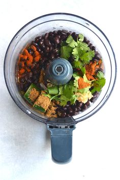 a food processor with black beans, carrots and cilantro in it on a white surface