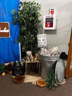 an office cubicle with stuffed animals and trash cans on the floor next to it