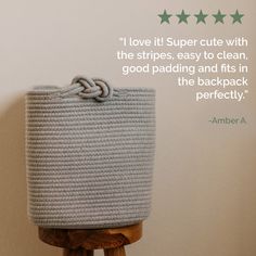 a gray basket sitting on top of a wooden stand next to a wall with a quote above it