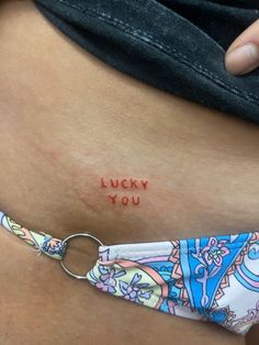 a woman's stomach with the words lucky you tattooed on her lower side belly