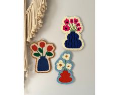 three embroidered patches with flowers and vases on them