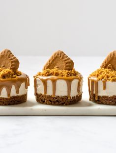 three mini desserts with frosting and peanut butter toppings on a white platter