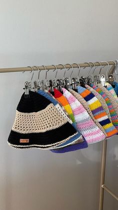 multicolored knitted hats hanging on clothes rack with metal bar and hooks