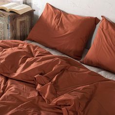 an unmade bed with orange sheets and pillows