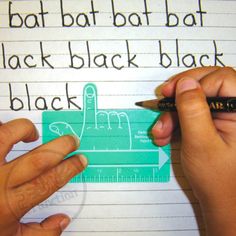 two hands are writing on a piece of paper with a ruler and black pen in front of it