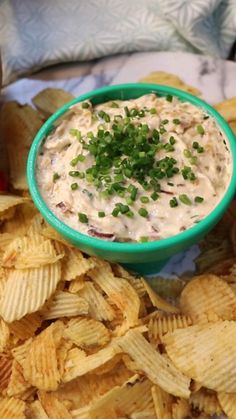 a green bowl filled with dip surrounded by chips